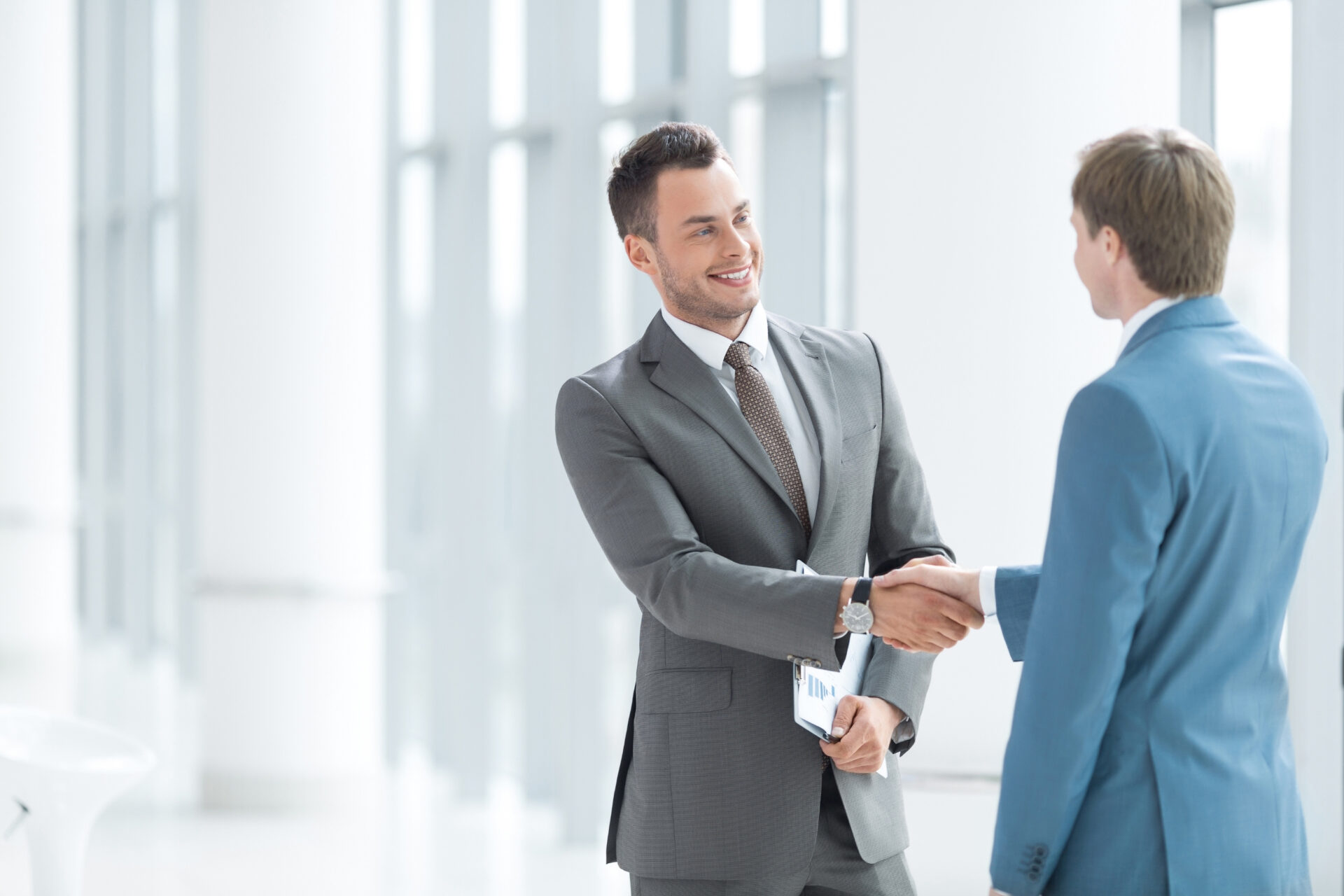 An image of business partners shaking hands and smiling.