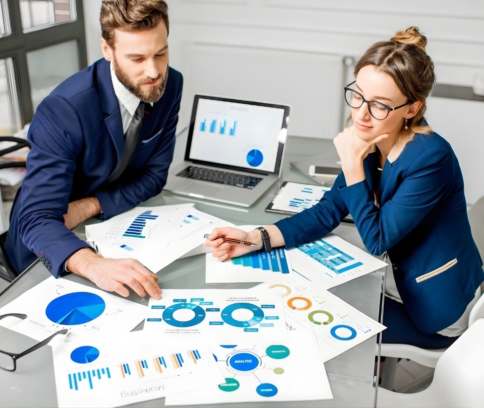 An image of workplace professionals looking analyzing charts from a data dashboard.